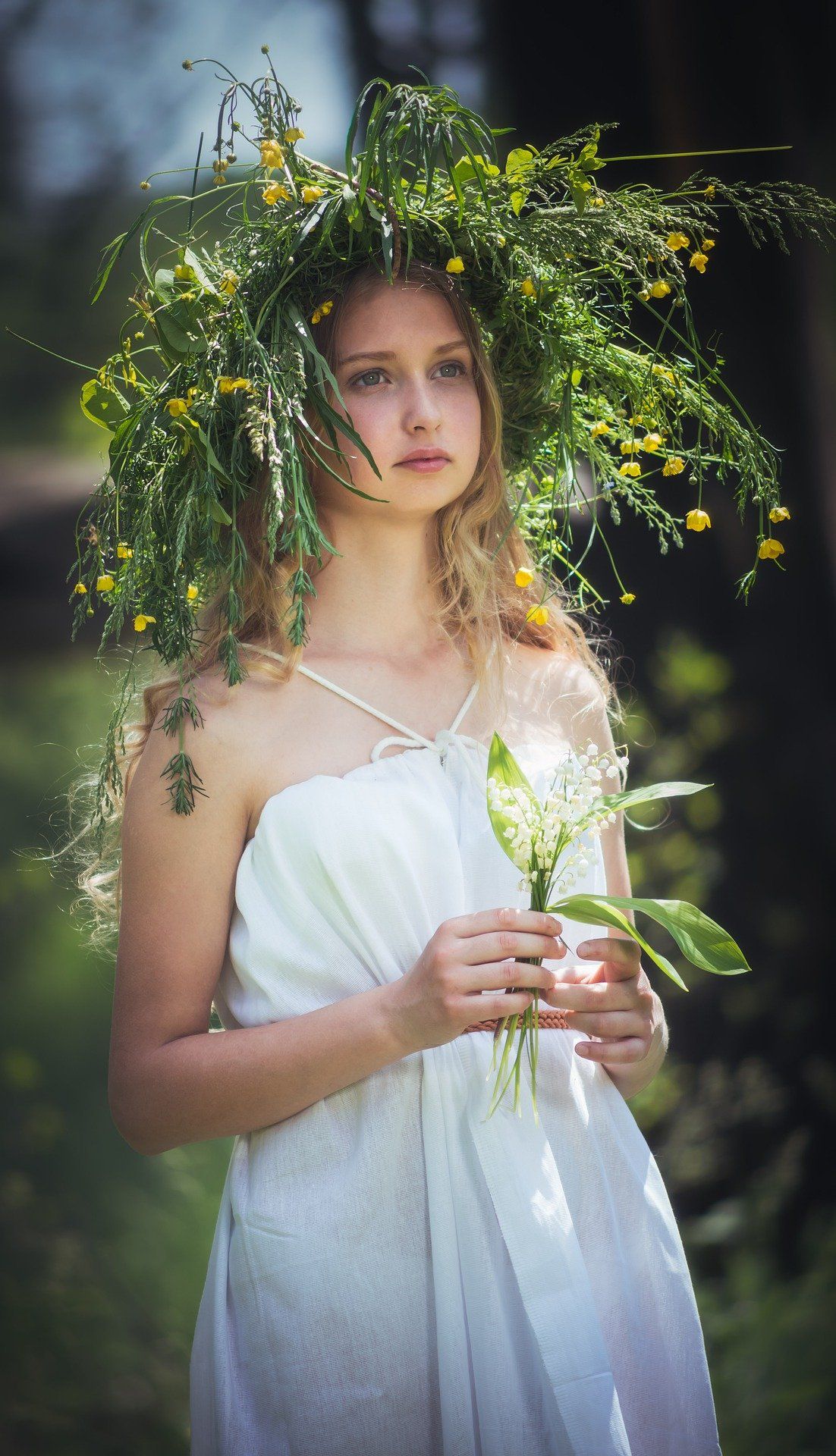 Mädchen mit Wiesenhut und Blumen in der Hand.